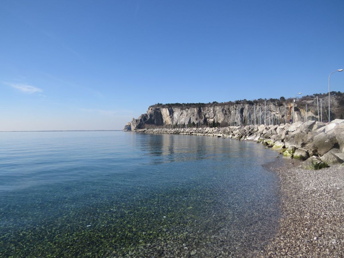 the perfect pebble beach at Sistiana, with Duino castle just visible at the end of the cliff in the distance.. the perfect pebble beach at Sistiana, with Duino castle just visible at the end of the cliff in the distance..
